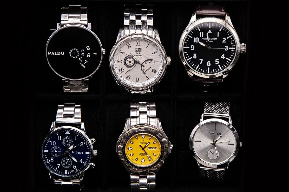 Several watches arranged in a watch box on a wooden surface