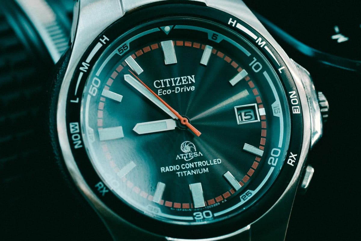 A close-up of a watch dial and hands with warm reflections