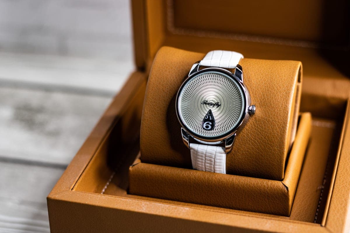An automatic watch resting in a watch winder on a dark surface